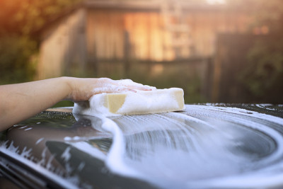 A woman washes the roof of a car