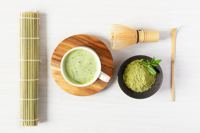 绿色抹茶拿铁和茶配件在白色木质背景顶视图。日本茶道观念。