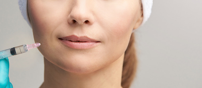 女性面部美容治疗。Biorevitalization皮肤治疗。医生插入填充。女孩诊所面部中观治疗。医