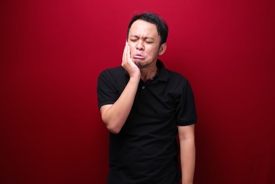 亚洲年轻男子牙齿问题与受伤的情绪穿黑衬衫。