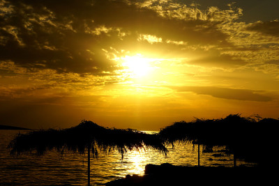 太阳伞的剪影在生机勃勃的海面夕阳前