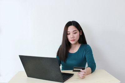 亚洲女性用笔记本电脑网购信用卡支付，烘焙
