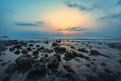 海滩日出与岩石和海浪与太阳可见