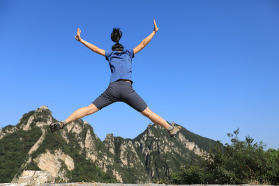 成功的女性徒步旅行者在山顶上跳跃