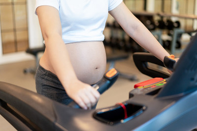 活跃的孕妇在瑜伽室健身中心锻炼。年轻的孕妇抱着怀孕的肚子里的婴儿。孕产妇产前护理与妇女怀孕的概念。