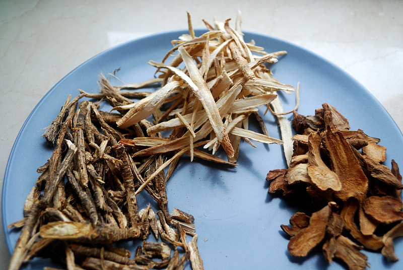盘子里的各种中药。方凤、白竹、黄芪根切成片晒干。