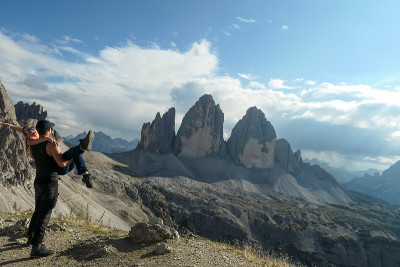 一个男人抱着一个女人坐在Sextner Stein的上面，欣赏着意大利Dolomites著名的Dre