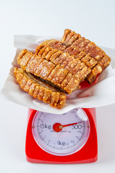 Close Up Deep Fried Crispy五花肉在孤立的背景下，泰国和中国食物的红色秤称重