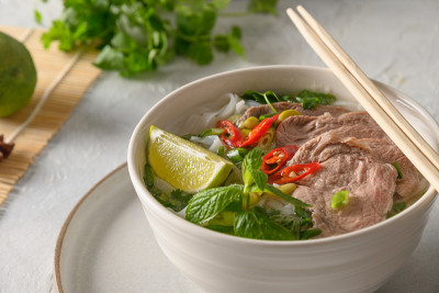 白碗牛肉粉汤，背景柔和。越南菜。