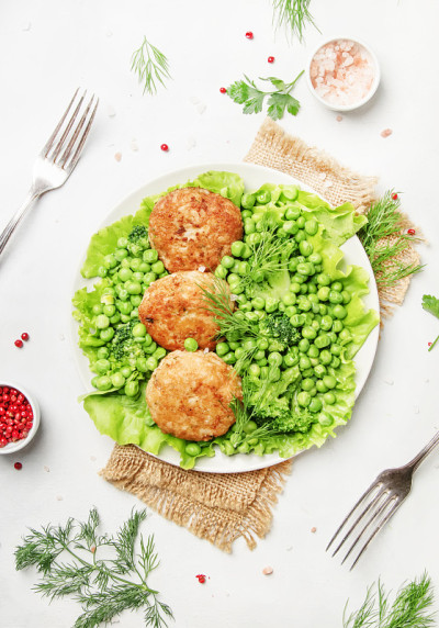 鱼丸或鳕鱼肉片配绿色蔬菜，俯视图