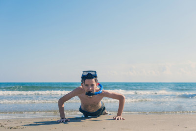 13岁的男孩在海滩上拧着潜水面罩和潜水管。旅游和夏季概念。