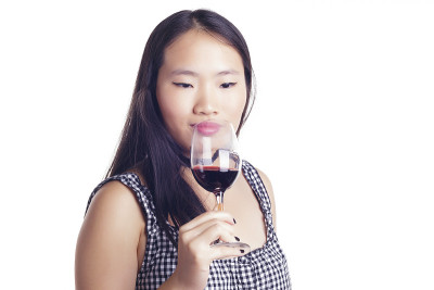 一个亚洲女孩拿着一杯红酒。