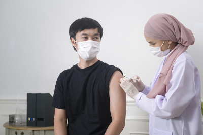 女穆斯林医生向患者手臂注射covid-19疫苗、covid-19疫苗接种和保健理念