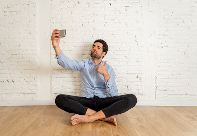 Young happy hipster blogger man filming a video or
