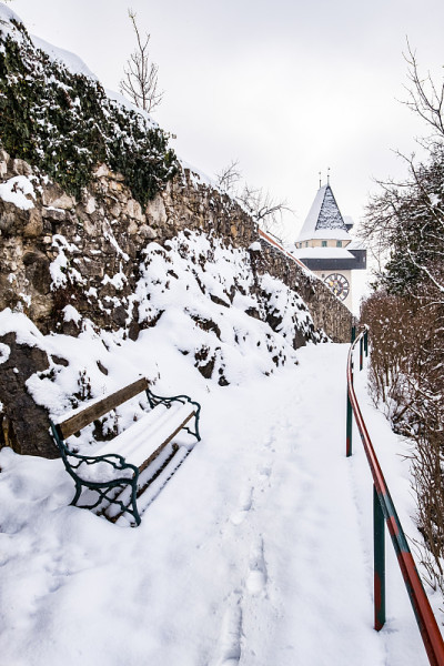 雪覆盖的长凳和通往格拉茨乌尔特姆钟塔的小路
