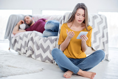 可悲的女人在看她男人的手机