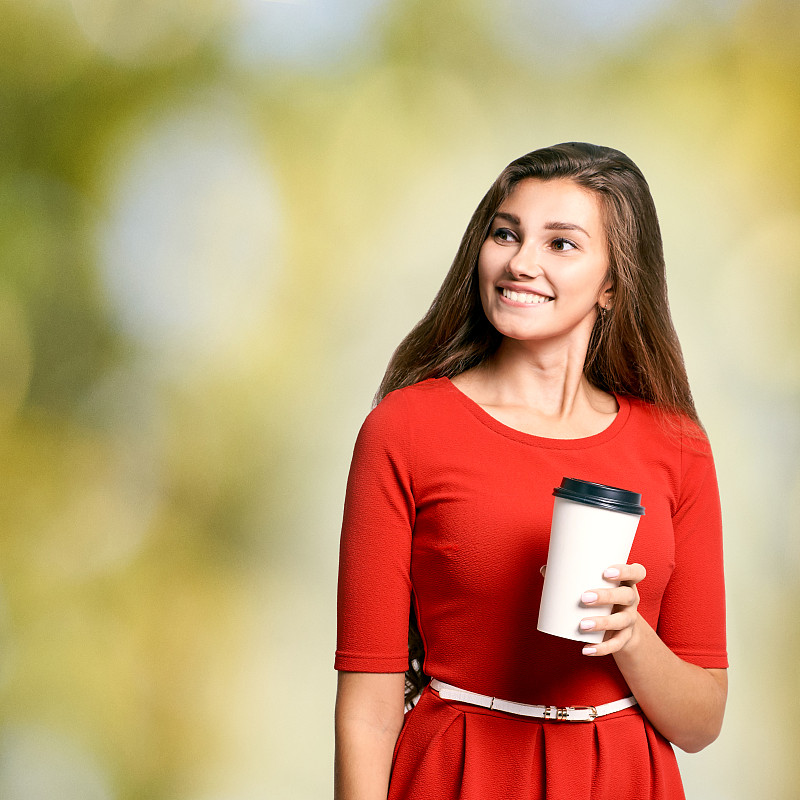 young Girl hold takeaway cup fo coffee. Red dress.