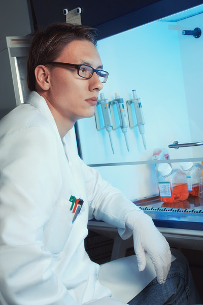 年轻的男性科学家坐在细胞培养箱旁