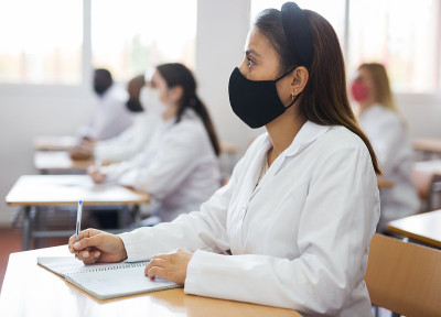 戴面具的妇女与同事一起学习