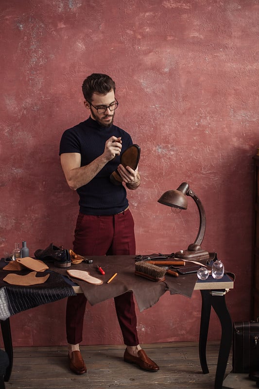 Young man holding a knife and going to repair shoe