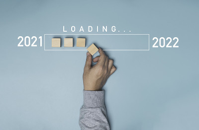 手把木制立方体与信息图表加载从2021年到2022年的蓝色背景，准备圣诞快乐和新年快乐的概念。