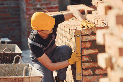 砖墙的尺寸。建筑工人穿着制服和安全设备在建筑上工作