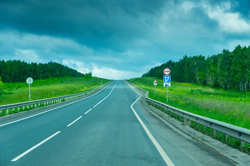 空旷的乡村道路，有禁止超车和方向标志