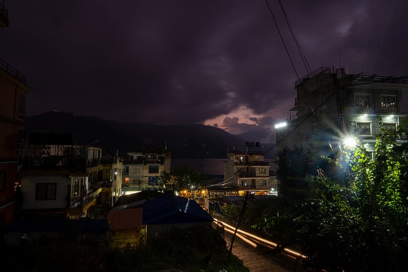 尼泊尔博卡拉市和费瓦湖的夜景。被照亮的商业街和过往车辆发出的模糊灯光