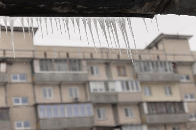 危险的冰柱悬挂在满是积雪的屋顶上。冬季小镇的街道上有巨大的冰柱