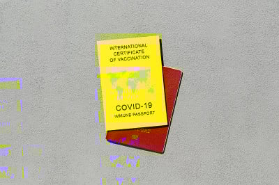 免疫护照，作为Covid-19疫苗接种的证明，是国际旅行的必要条件。灰色背景上的黄色疫苗接种证书。俯