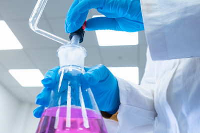 近距离观察科学家使用滴定分析法来研究水样的化学性质。科学家拿着装有粉红色溶液的锥形瓶。