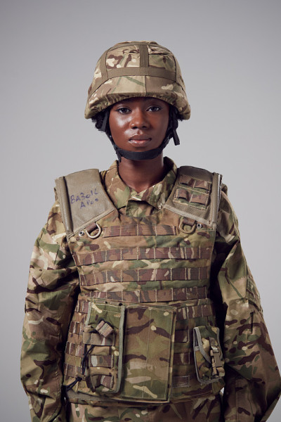 摄影棚里的严肃的年轻女士兵在军服朴素的背景下