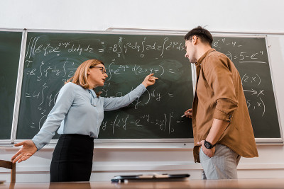 女教授在教室里指着方程式给学生看