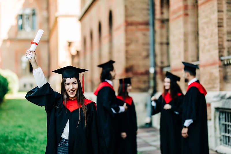 教育、毕业与人观念。一群快乐的国际学生在学位板和学士学位袍与文凭