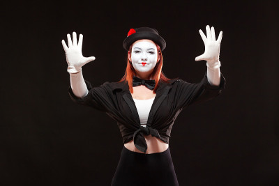 女哑剧艺术家表演的肖像，孤立在黑色背景上。一个女人正对着镜头做手势