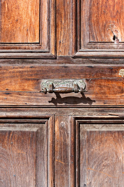 Old bronze door handle and aged wooden door, Antig
