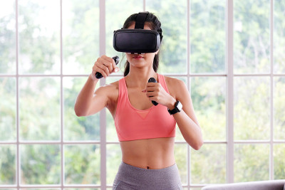 亚洲女性虚拟现实头盔，同时在家里锻炼，健康亚洲女孩戴vr眼镜互动锻炼，电子运动，女性和可穿戴技术
