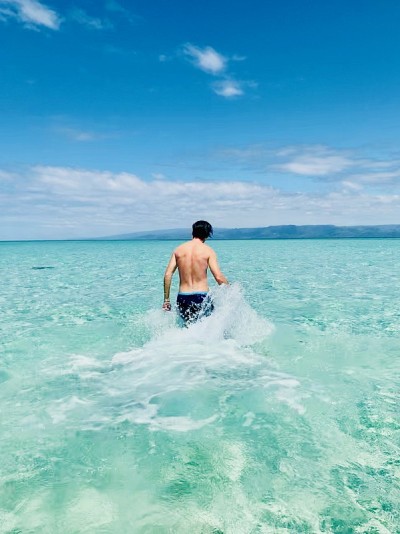 一个人走在浅海和蓝绿色的水在夏天。
