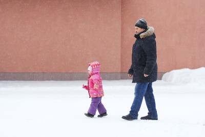 Man and child walking in snowy park in winter