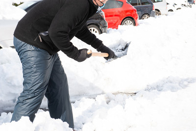 一名身穿防雪衣和防雪鞋的白人男子正在帮助铲雪。本空间