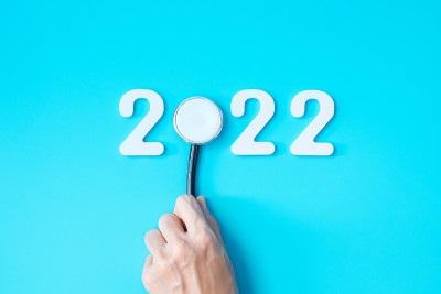 手持听诊器，蓝色背景为2022号。祝健康、保险、健康和医疗理念新年快乐