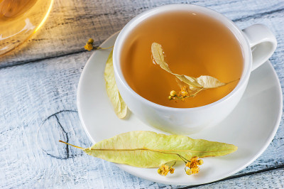 俯视图白色杯菩提树茶或盛开的椴树，椴木，在乡村复古白色木制桌子上。凉茶理念，精挑细选