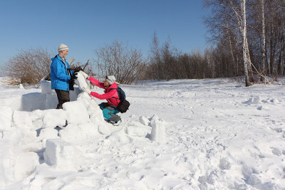 男人和女人在冬天的雪地上建造冰屋