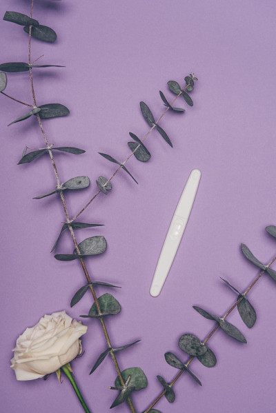 俯视图排列妊娠试验，花和绿色桉树叶孤立在紫色