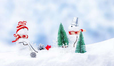可爱的雪人戴着滑稽的帽子和围巾，杉树深埋在雪堆里