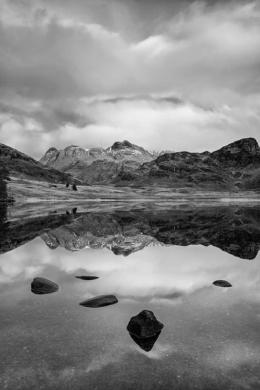 美丽的黑色和白色的冬天日出在湖区Blea Tarn与雪覆盖的Langdale派克在远处