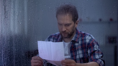 悲伤的男人躲在雨窗后读信，银行赊账逾期，贫穷