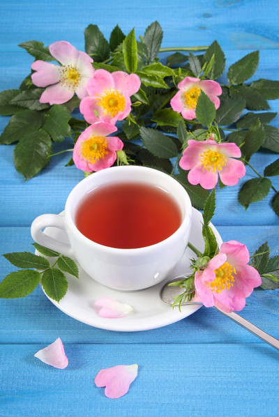 一杯热茶和蓝板上的野玫瑰花