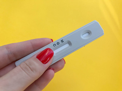 医疗程序。亮黄色背景上的冠状病毒测试。女孩与明亮的红色指甲持有一条。IgG和IgM抗体检测