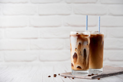 冰咖啡拿铁卡布奇诺在一个高脚杯奶油或牛奶andÂ coffeeÂ豆和吸管在白木背景。清凉可口的夏日茶